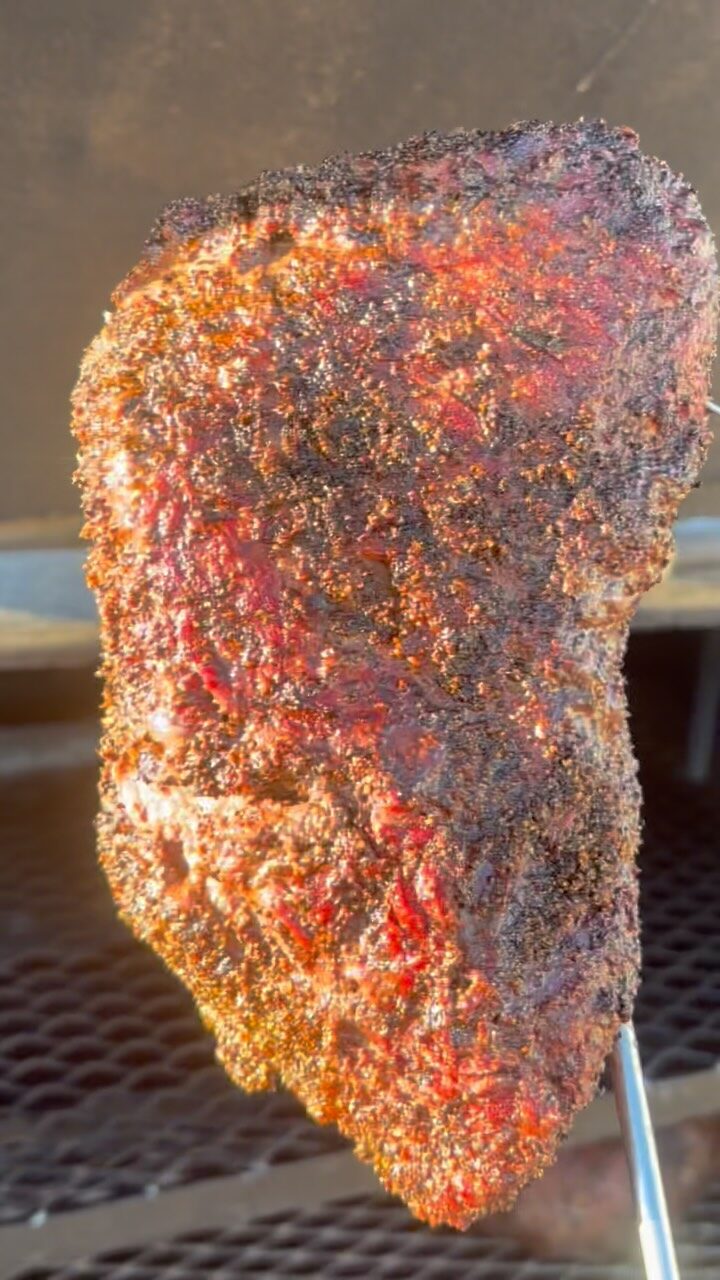 Their rubbed tri-tip on a hook over the pit in low sun