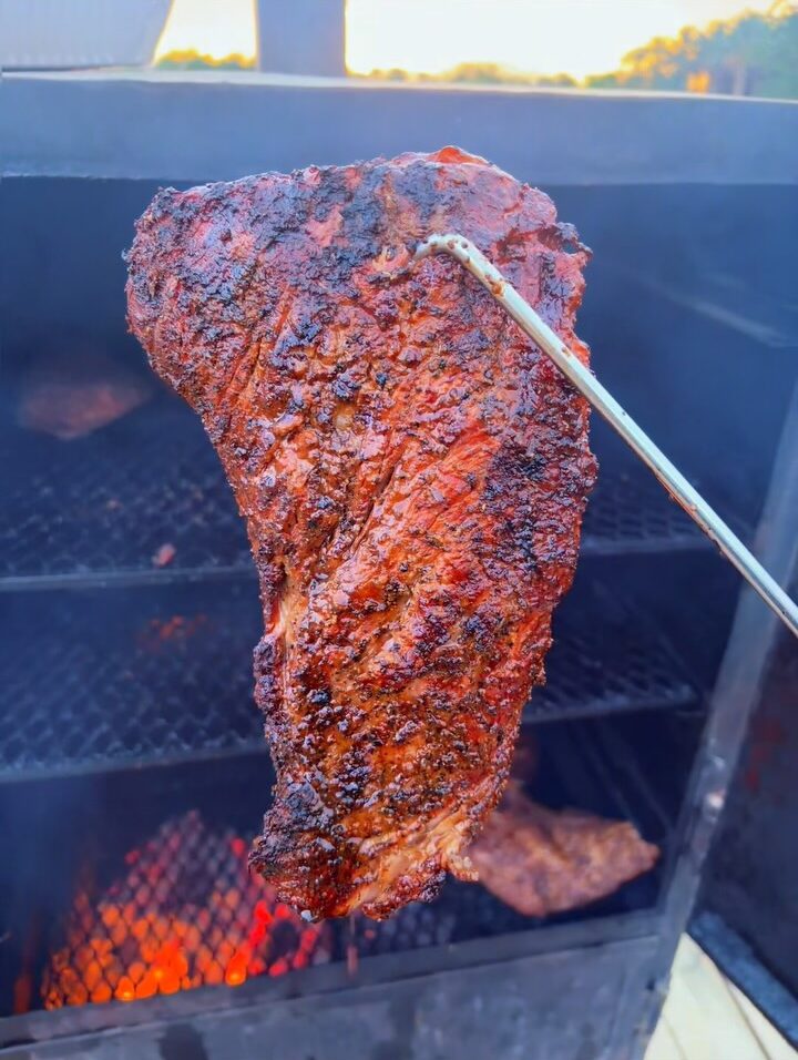 Their tri-tip on a hook over glowing coals, the dusk sky above